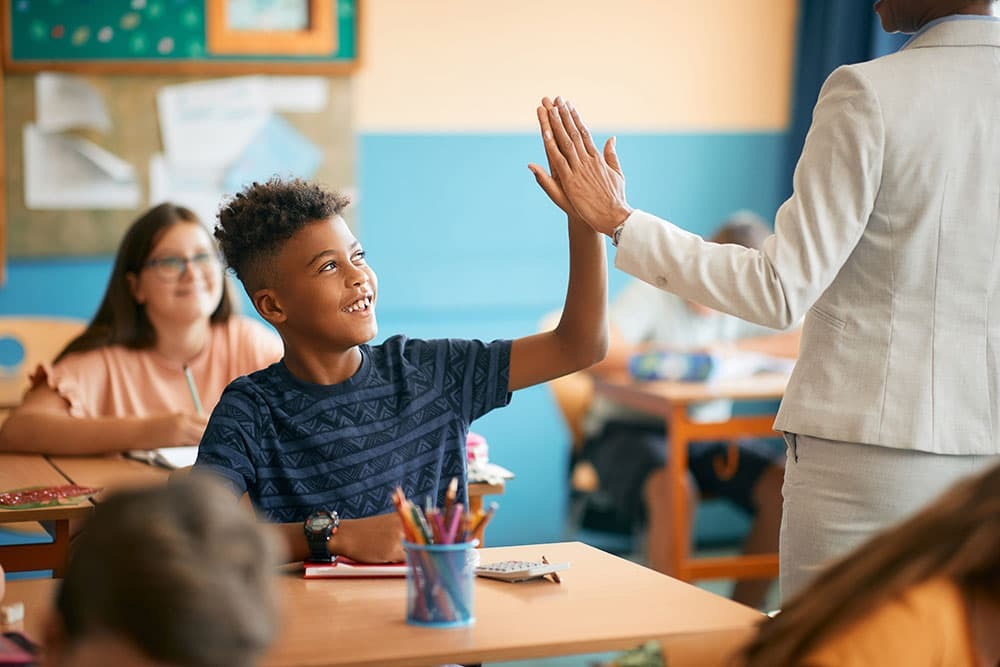 Student giving a high five to a teacher in a classroom